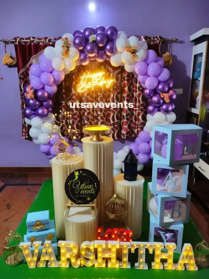 A lovely purple and white themed birthday setup. The balloon arch, neon sign, and personalized marquee letters make for a beautiful and memorable celebration.