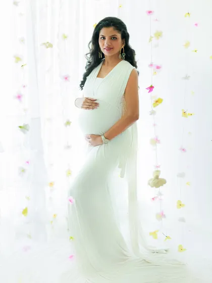 Cradling the miracle within. This mother-to-be looks like a goddess in a classic white gown, surrounded by a delicate curtain of flowers for an ethereal touch.