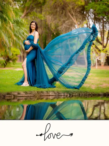 The reflection of a flowing blue gown in the water adds a magical touch to this outdoor portrait. The mother-to-be stands confidently, creating a powerful and artistic image.