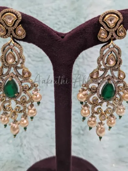 A close-up of the statement earrings from the antique-finish polki set. The intricate design, green stones, and pearl drops make them a standout piece, even when worn alone.
