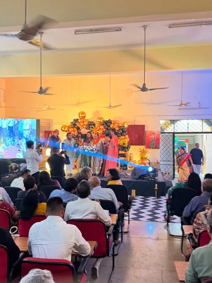 A wide shot of the retirement event in progress, showing the decorated stage and the audience.