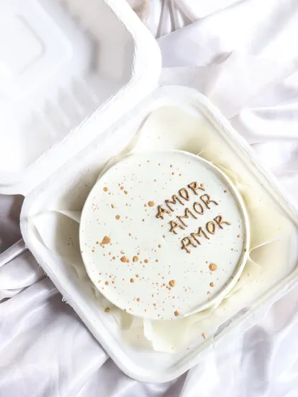 A simple and sweet bento cake with 'Amor Amor Amor' written on it, decorated with gold splatters.