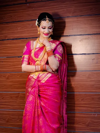 A full-length portrait of the bride in her gorgeous pink wedding saree.