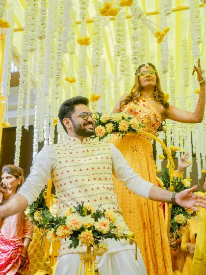 A close-up of the couple enjoying their unique Haldi entry, surrounded by floral decorations on the rickshaw.