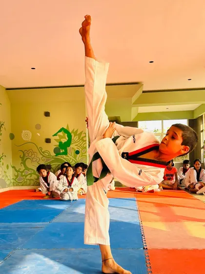 Another student demonstrating an impressive high side kick, showing incredible flexibility and control.