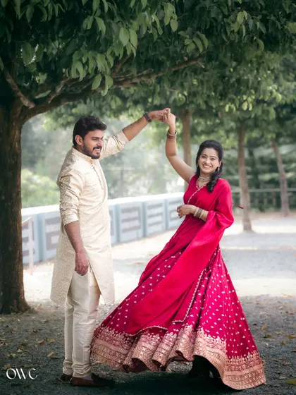 A fun and twirling dance move captured in a park, showcasing the vibrant color of the lehenga and the couple's happiness.