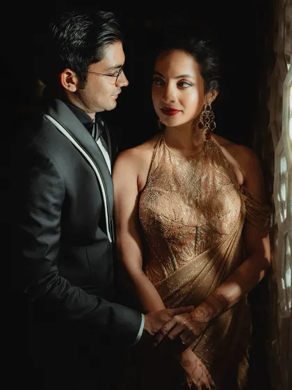 An intimate portrait of the couple. The soft lighting highlights the golden shimmer on her eyelids and the rich color of her lipstick.