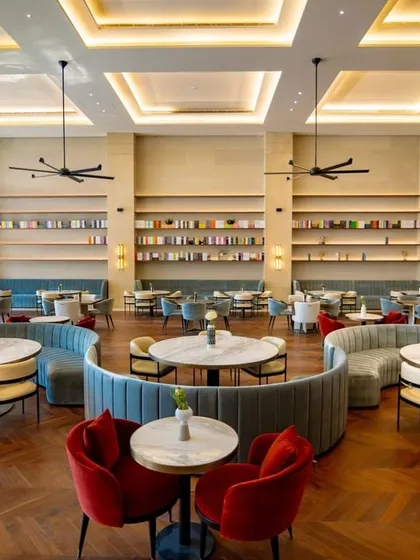 Another view of the main dining hall at the Elevate Clubhouse, showcasing the variety of seating options. The mix of curved banquettes, round tables, and smaller setups allows the space to feel vibrant and full, whether for a quiet lunch or a large gathering.