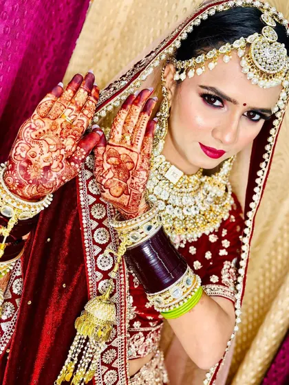 This portrait captures the essence of my bridal service. The focus is on a flawless makeup application with a bold lip, paired with stunningly detailed henna, creating a look of pure elegance.