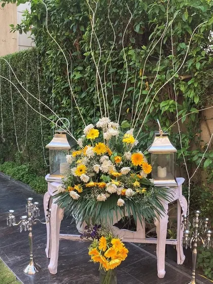 A beautiful floral arrangement for an outdoor event. We used a mix of yellow and white flowers with elegant lanterns to create a welcoming and picturesque corner.