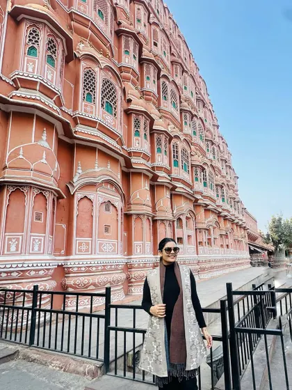 A travel memory from Jaipur, standing in front of the iconic Hawa Mahal. I'm wearing a layered look with a black base and two different shawls for warmth and style.
