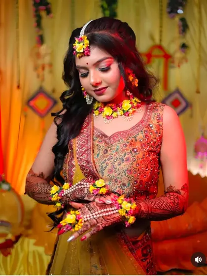 A close-up of the bride admiring her hands, adorned with both henna and beautiful floral accessories.