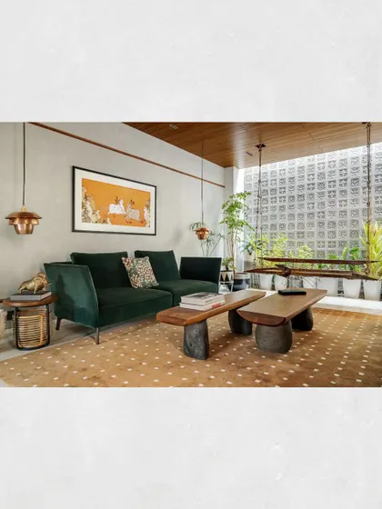 The formal living area in Kamala Residence, where a custom swing, a deep green sofa, and a live-edge coffee table sit before a wall of breeze blocks that filter light beautifully.