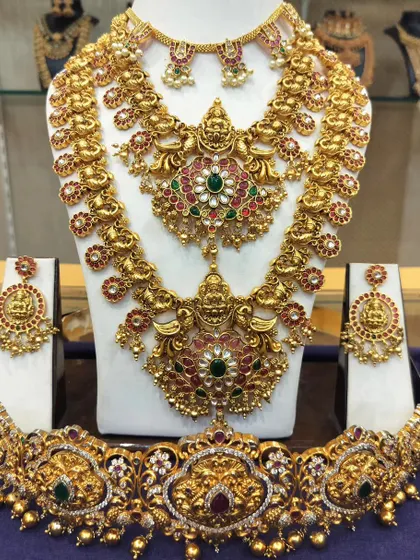 A stunning temple jewellery set with a mix of Lakshmi and peacock motifs, studded with red, green, and white stones.