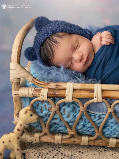 A sweet little bear in a basket. The knit bonnet with ears and the cozy blue tones make this an incredibly adorable and heartwarming portrait.