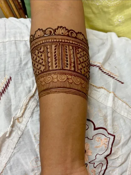 A close-up of a detailed armband, showcasing the fine line work and consistent application of the henna paste.