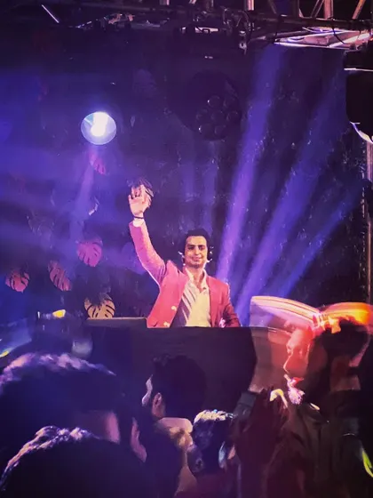 A shot from behind me, showing the crowd's reaction as I wave to them. The purple lighting and tropical leaf silhouettes create a cool, club-like atmosphere.