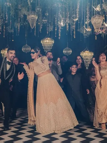 The energy is high as the couple and their guests dance the night away on a chevron-patterned floor under a ceiling of hanging chandeliers.