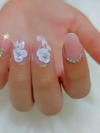 A close-up view of our 3D floral art on a single nail, showing the delicate petal work and rhinestone details.