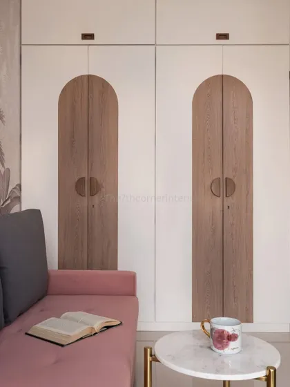 The wardrobe in the guest room features a unique arched design in a wood finish, contrasting beautifully with the white doors. This custom detail adds a touch of playful elegance to the space.