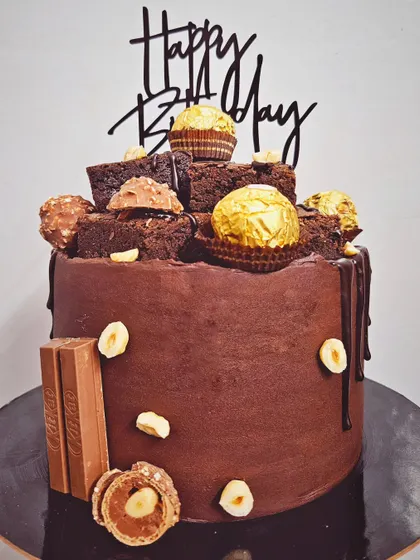 A cake that screams chocolate! A decadent chocolate truffle and biscoff cake loaded with brownies, Ferrero Rocher, and KitKat.