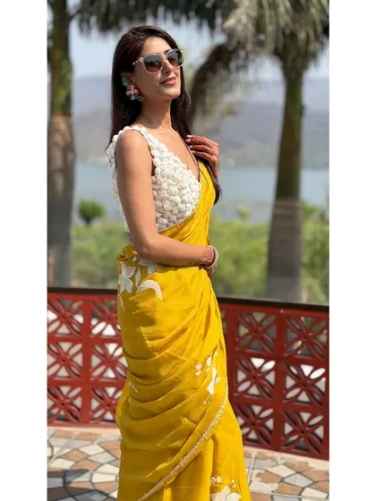 A side profile in the yellow organza saree, showing how the floral hand-painted details are placed along the drape. It's these thoughtful design elements that make an outfit truly special.