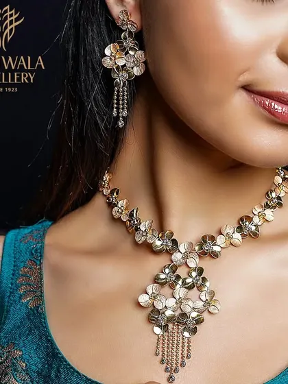 A stunning floral necklace and earring set in gold. The intricate, three-dimensional flowers create a beautiful and artistic statement, perfect for a special occasion.