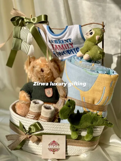 A different angle of the 'Current Family Favorite' hamper, showing the thoughtful arrangement of the teddy bear, dinosaur toys, and baby booties in a sturdy rope basket.