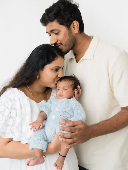 A loving family portrait, with both parents kissing their newborn's head.
