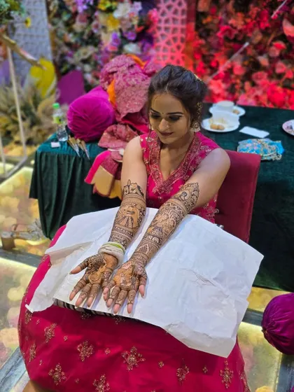 This bride is all smiles with her completed bridal mehandi. The design features classic bride and groom figures, a timeless choice for wedding henna.