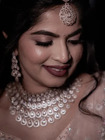 A classic bridal portrait, showcasing her elegant makeup and diamond jewelry set. The soft smile captures her happiness on her special day.