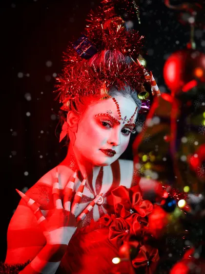 The dramatic red lighting enhances the festive mood of this Christmas makeup.
