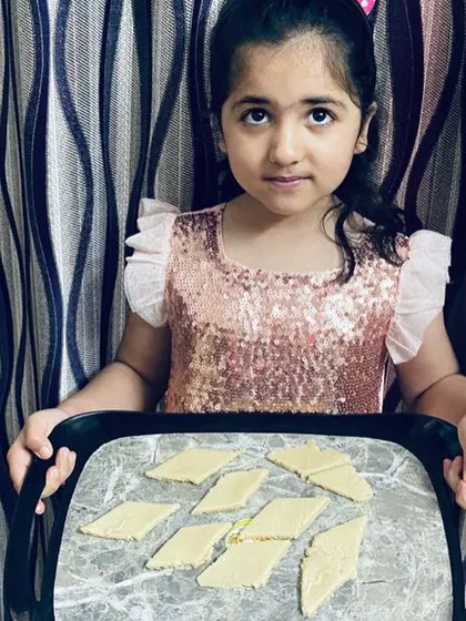 A proud student with her tray of freshly made sweets. The process of creating something edible and delicious is a deeply satisfying and multisensory learning experience for children.