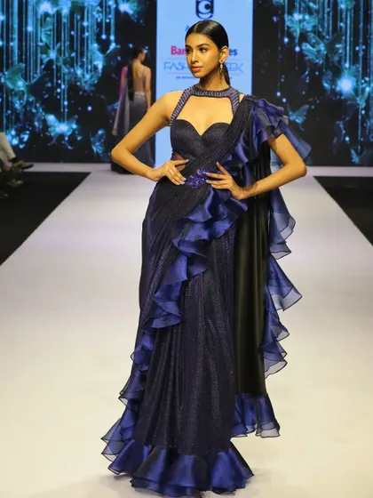 Another angle of the dark blue ruffled saree gown on the runway. The shimmering fabric and cobalt blue accents make it a truly eye-catching piece for any evening event.