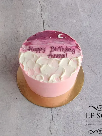 A dreamy, minimalist cake with a painted sky effect. This half-kg Ferrero Crunch cake features a pink and purple sky with a crescent moon, all created with buttercream.