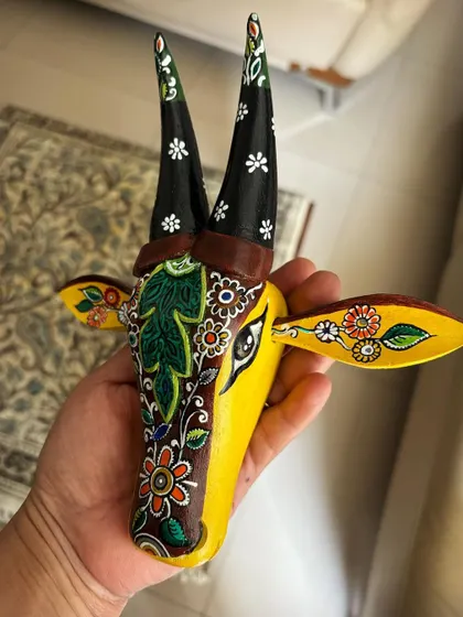 A view of the Kalamkari Nandi in hand, showing its scale and the fine, flowing lines of the design that wrap around its face.