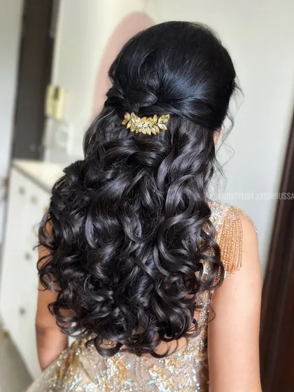 A half-updo with tight, defined curls and a simple twist at the back, adorned with a gold leaf clip. This is a glamorous look for a cocktail party or reception.