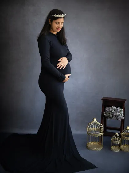 A classic and elegant solo maternity portrait. The mom-to-be wears a simple black gown and a delicate tiara, creating a look of regal grace.