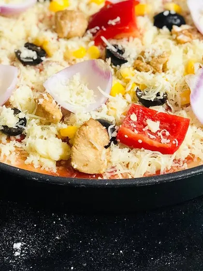 A homemade pizza ready for the oven. We will assemble this colorful chicken pizza in class, starting with a fresh dough base and adding all your favorite toppings.