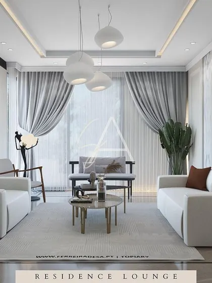 A bright and airy residence lounge with a clean, white color scheme. The sculptural pendant lights and wall art add a contemporary, artistic touch, while the wooden armchairs provide warmth.
