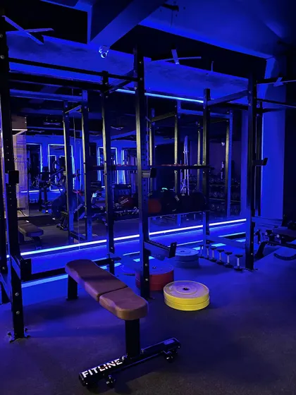 A look at our strength section, complete with two squat racks and plenty of plates, all under our signature blue lighting. We're officially open and ready for you.