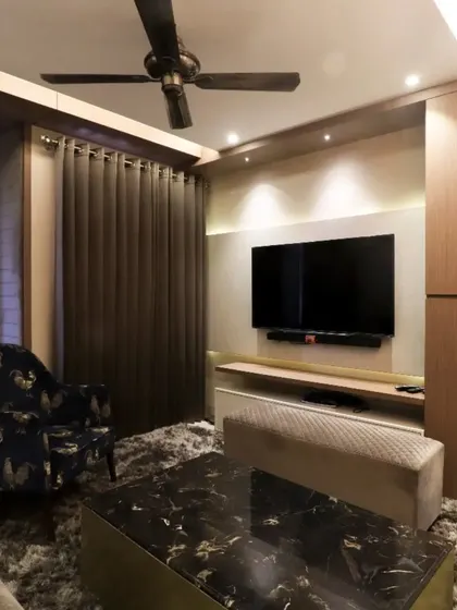 A cozy media room with a dark marble coffee table and a plush rug. The design focuses on comfort and creating an immersive entertainment experience.