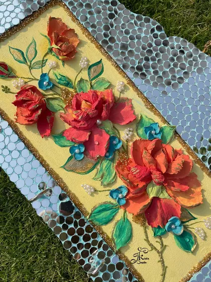 A unique key holder that combines sculpture art with mosaic mirror work. The bright red and orange flowers pop against the yellow background, while the mirrored border adds a touch of glamour.