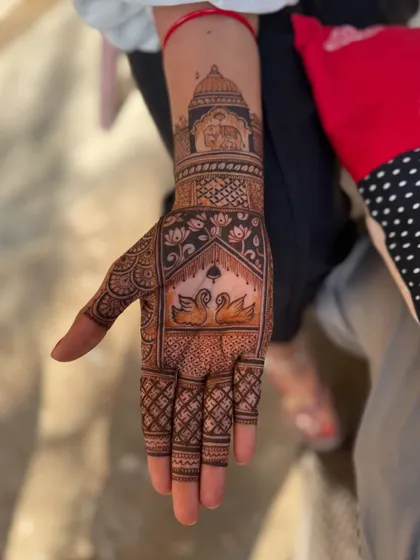 This intricate palm design features a pair of swans below a palace dome, with an elephant motif on the wrist. It's a great example of combining animal and architectural elements.