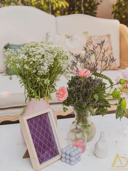 A charming tabletop arrangement with fresh flowers in glass vases and a small framed print, adding a personal and delicate touch to the decor.