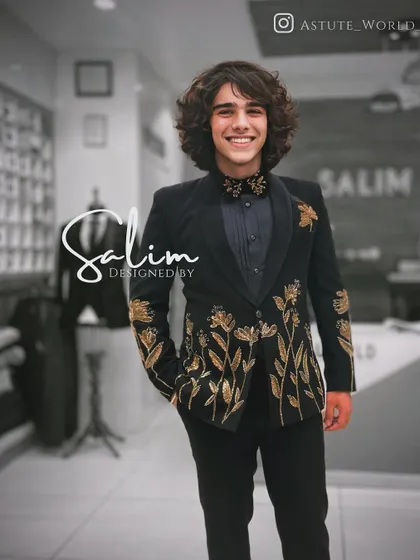 A young client in a black velvet tuxedo with gold floral embroidery. This design is elegant and timeless, perfect for any formal celebration.