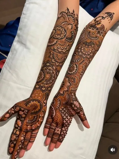 This bridal design includes a palanquin (doli) motif on one arm, a classic part of the wedding story, paired with floral patterns on the other.
