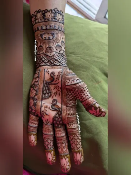 A lovely design featuring two peacocks on the palm. The trees and elephant band on the wrist add to the narrative of the piece.