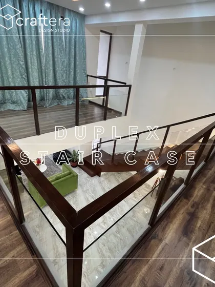 A view of the duplex staircase from the upper floor, showing the glass and wood railing that provides safety without obstructing the view, maintaining an open and airy feel.