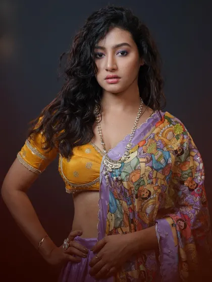 A studio portrait with a modern, artistic lehenga. The curly hair and confident pose give this traditional outfit a contemporary twist.